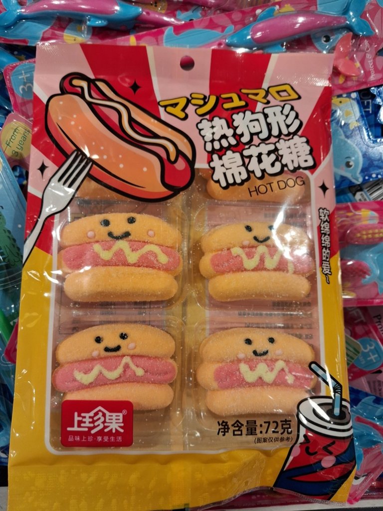 Fargerik plastpakke med kinesisk skrift og sukkerdekkede marshmallows i form av pølse i brød med smilefjes.
